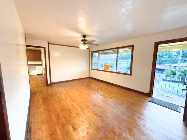 an empty room with wooden floor and windows