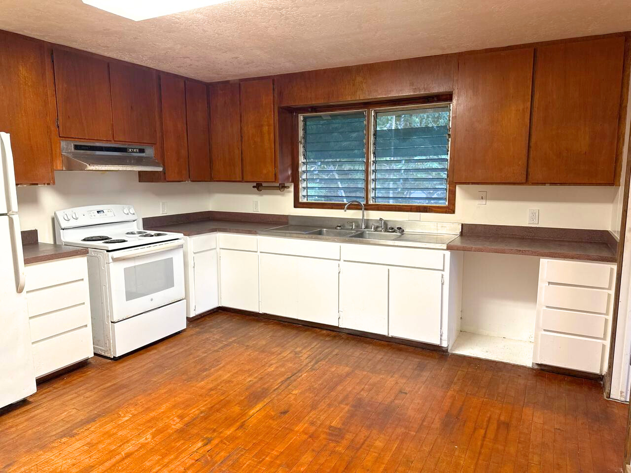 15-1485 Post Road Pahoa, HI 96778 - Photo 7 of 18 a kitchen with stainless steel appliances granite countertop a stove a sink and white cabinets with wooden floor