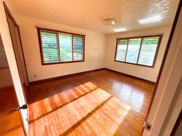 a view of an empty room with a window and wooden floor