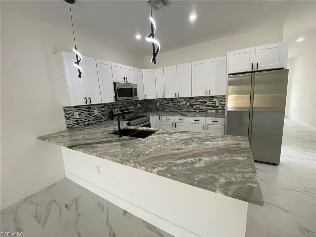 a kitchen with stainless steel appliances granite countertop a sink a refrigerator a counter top space and cabinets