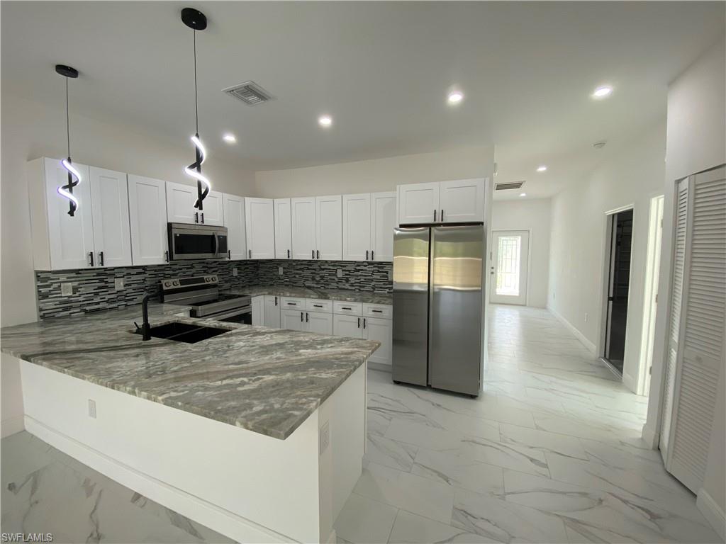 5444 Billings Street Lehigh Acres, FL 33971 - Photo 21 of 32 a kitchen with stainless steel appliances granite countertop a refrigerator a sink a stove a microwave and island