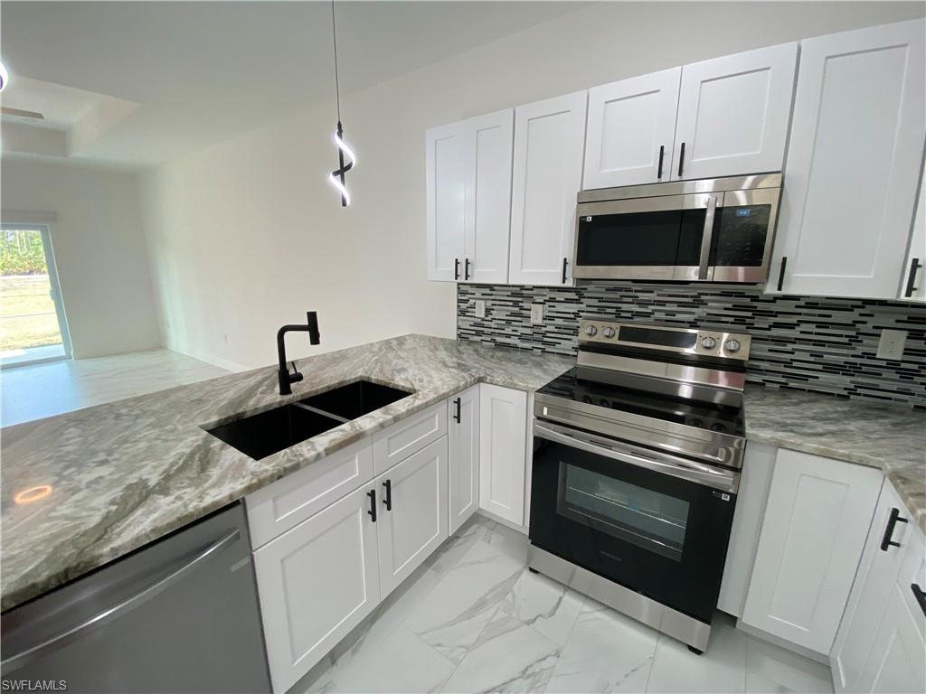 5444 Billings Street Lehigh Acres, FL 33971 - Photo 26 of 32 a kitchen with granite countertop a stove sink and microwave