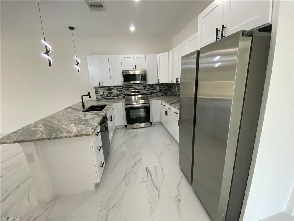 5444 Billings Street Lehigh Acres, FL 33971 - Photo 9 of 32 a kitchen with stainless steel appliances granite countertop a refrigerator a sink a stove and oven
