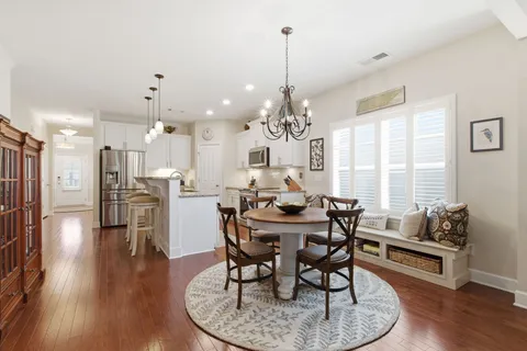 a view of a dining room and livingroom with furniture wooden floor a chandelier