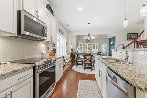 a kitchen with stainless steel appliances granite countertop a stove oven and a white cabinets