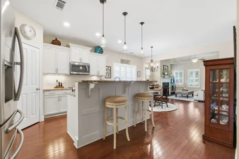 a kitchen with stainless steel appliances granite countertop a stove top oven a refrigerator a sink and a dining table with wooden floor