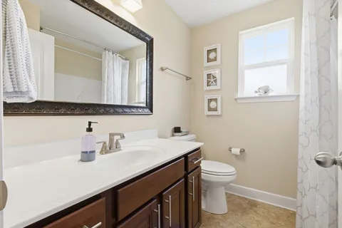 a bathroom with a sink a toilet a mirror and a window