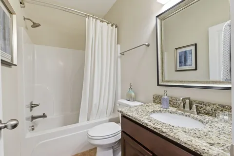 a bathroom with a granite countertop sink toilet and shower