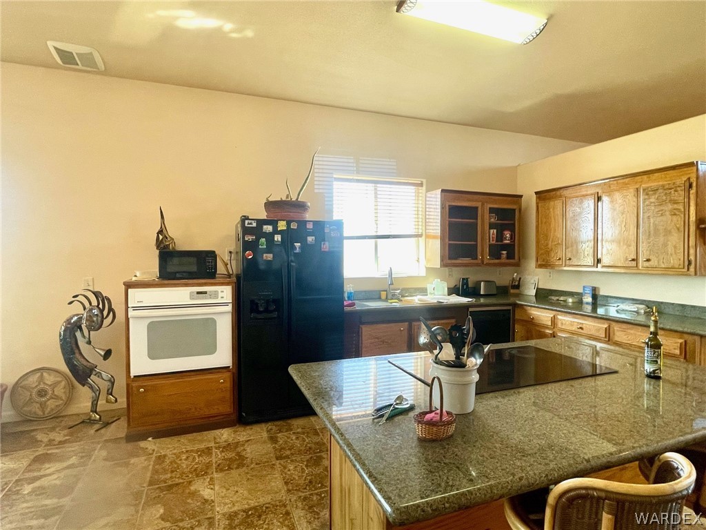 21477 South Sundance Kid Road Yucca, AZ 86438 - Photo 16 of 66 a kitchen with granite countertop a sink a stove and refrigerator