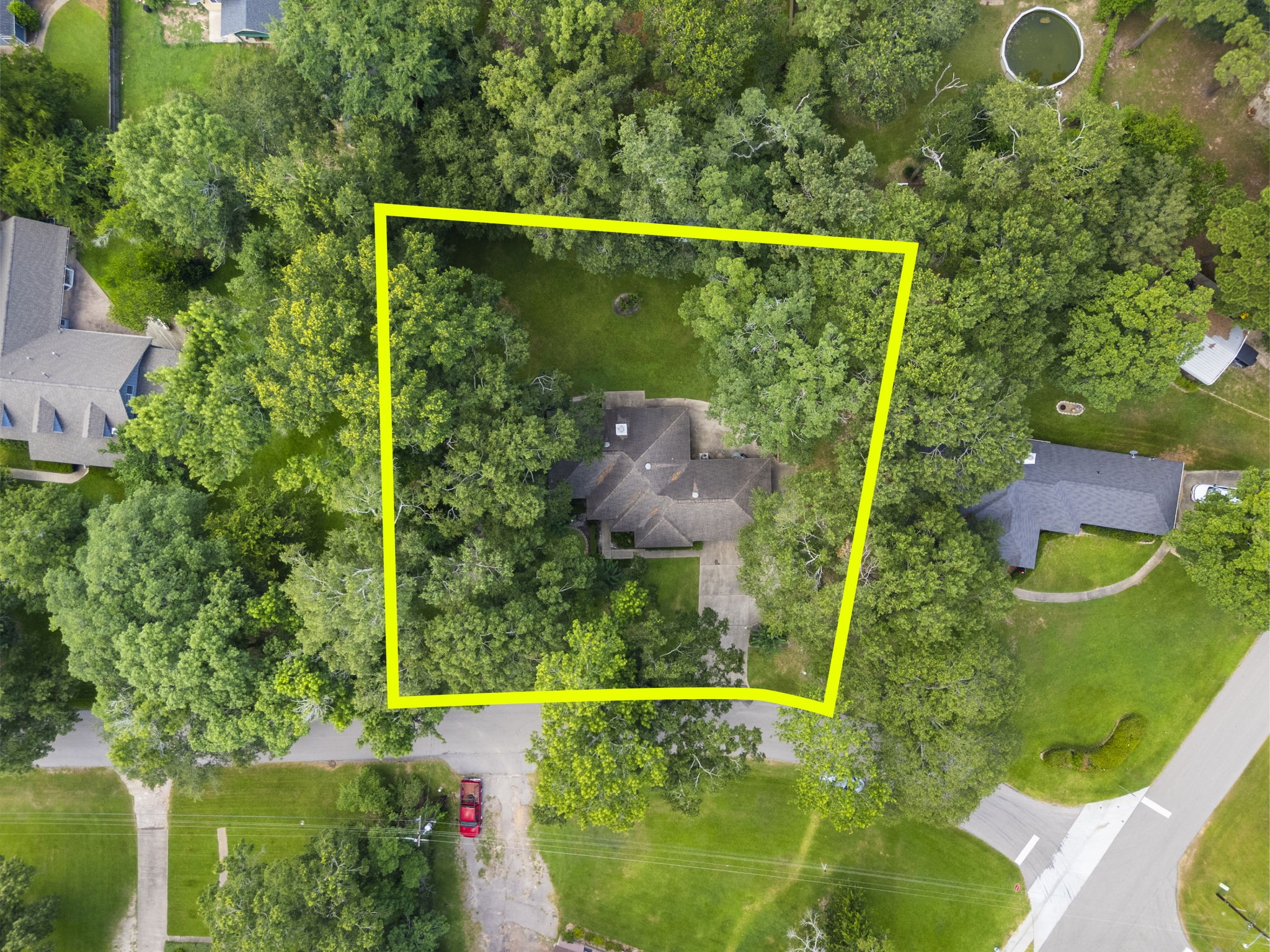 202 Sunset Boulevard Conroe, TX 77303 - Photo 46 of 50 This aerial photo shows a house surrounded by mature trees, offering ample privacy. The property is outlined in yellow, indicating a generous lot size in a lush, green neighborhood.