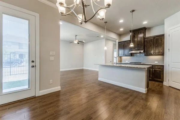 a large kitchen with stainless steel appliances kitchen island a large counter top and wooden floors