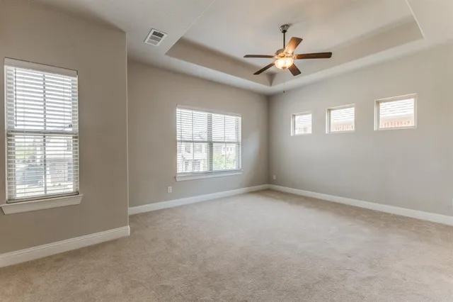 an empty room with ceiling fan and windows