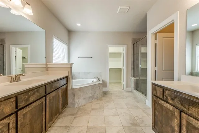 a spacious bathroom with a granite countertop sink a mirror and a bathtub