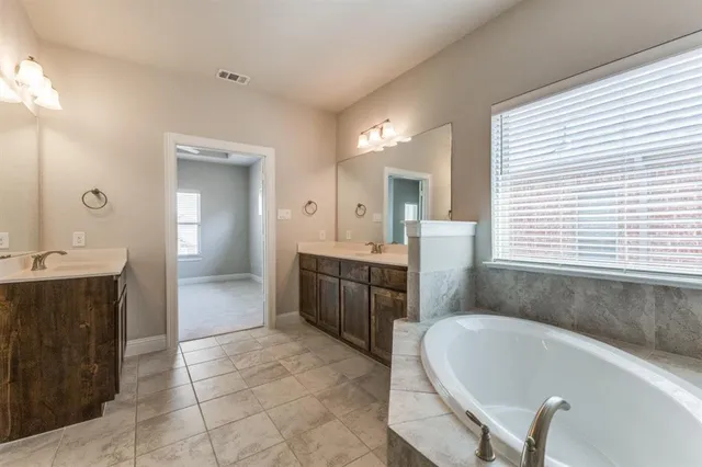 a large bathroom with a tub sink and mirror