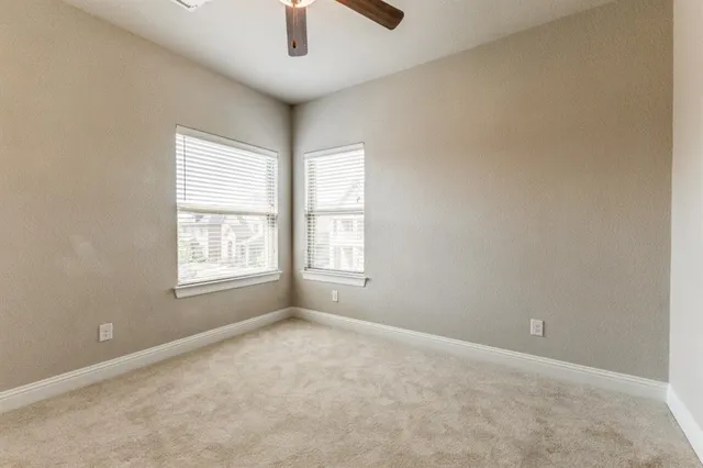an empty room with ceiling fan and window