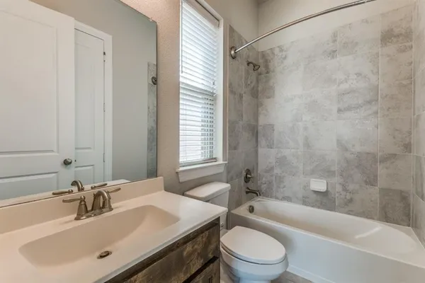 a bathroom with a bathtub shower sink vanity mirror and toilet