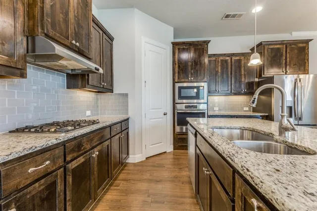 a kitchen that has a sink a stove and cabinets
