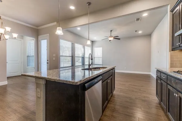 a kitchen with stainless steel appliances granite countertop a sink a stove and a wooden floors