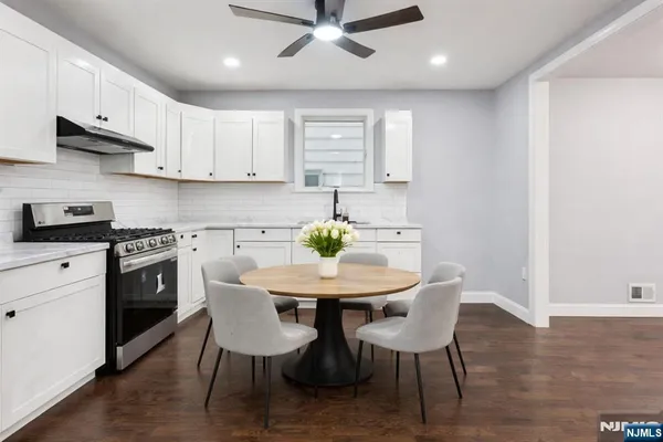 a kitchen with stainless steel appliances kitchen island granite countertop a dining table chairs and white cabinets