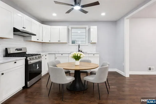 a kitchen with stainless steel appliances kitchen island granite countertop a dining table chairs and white cabinets