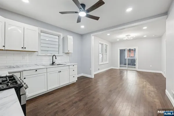 a large kitchen with stainless steel appliances granite countertop a stove and white cabinets with wooden floor