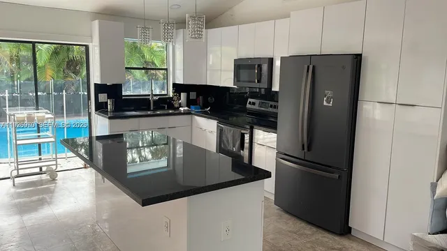 a kitchen with stainless steel appliances granite countertop a refrigerator a stove a microwave and a view of living room