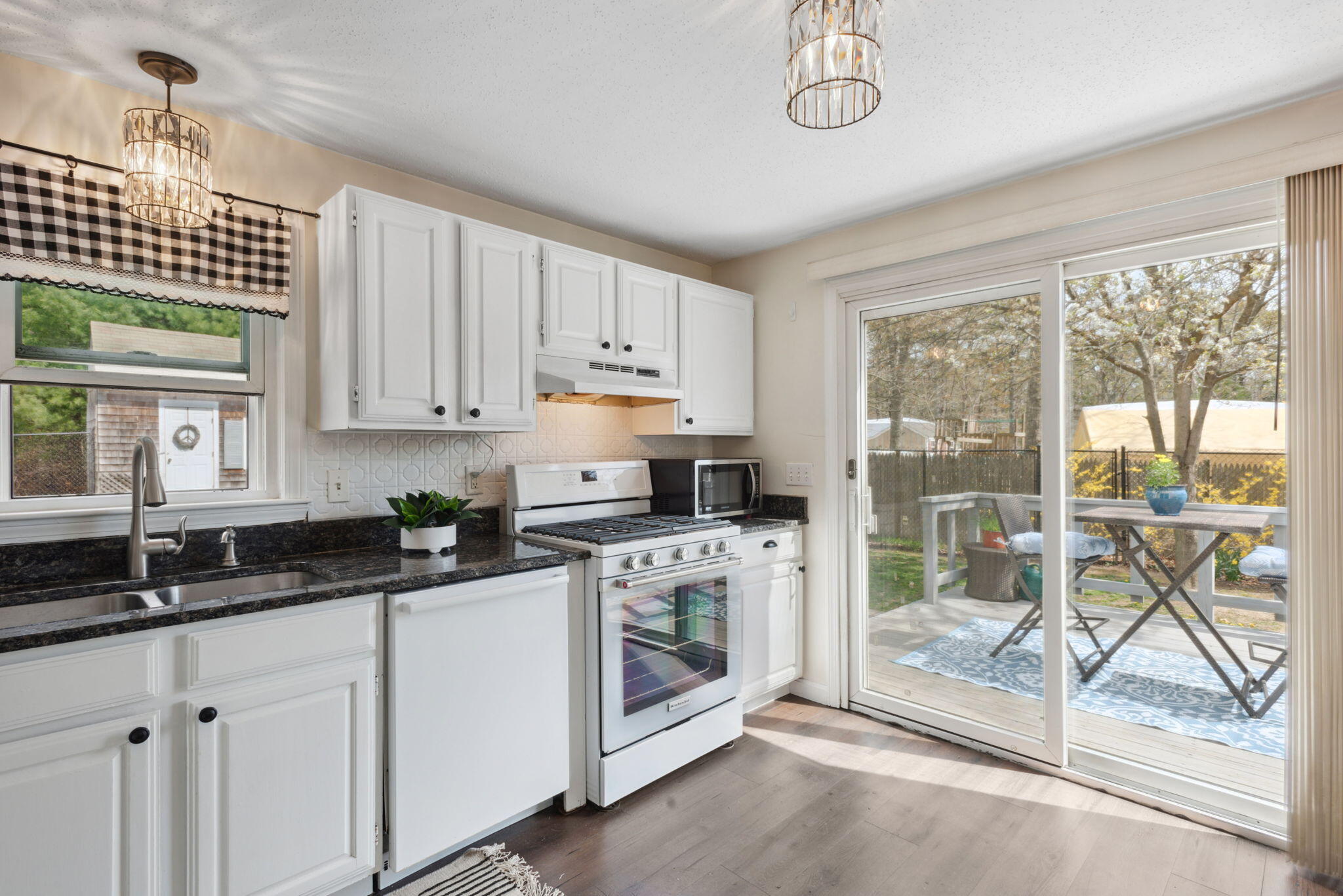 67 Degrass Road Mashpee, MA 02649 - Photo 12 of 24 a kitchen with granite countertop a stove a sink and white cabinets