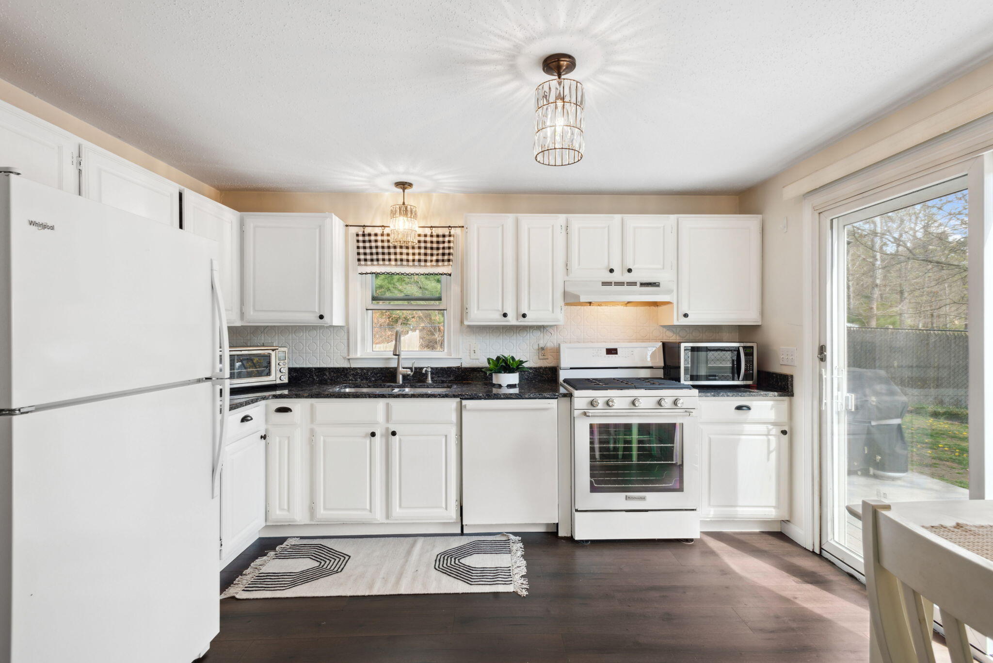 67 Degrass Road Mashpee, MA 02649 - Photo 10 of 24 a kitchen with granite countertop a refrigerator a stove a sink and white cabinets with wooden floor