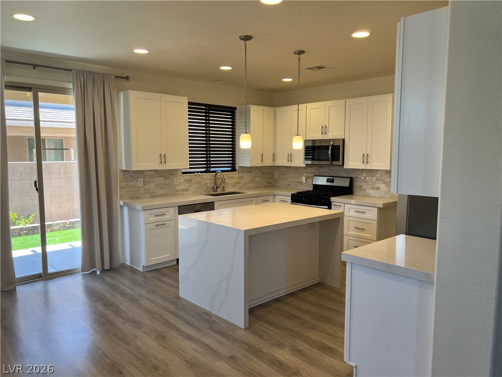 9581 Aberdeen Ridge Court Las Vegas, NV 89148 - Photo 10 of 25 A contemporary kitchen boasts a waterfall island and bright cabinetry, ideal for everyday living.