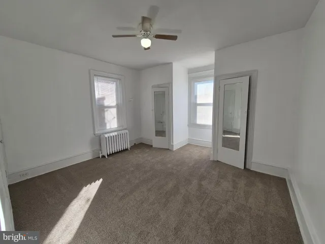 an empty room with windows and fan