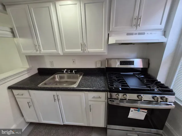 a kitchen with stainless steel appliances granite countertop white cabinets and a stove