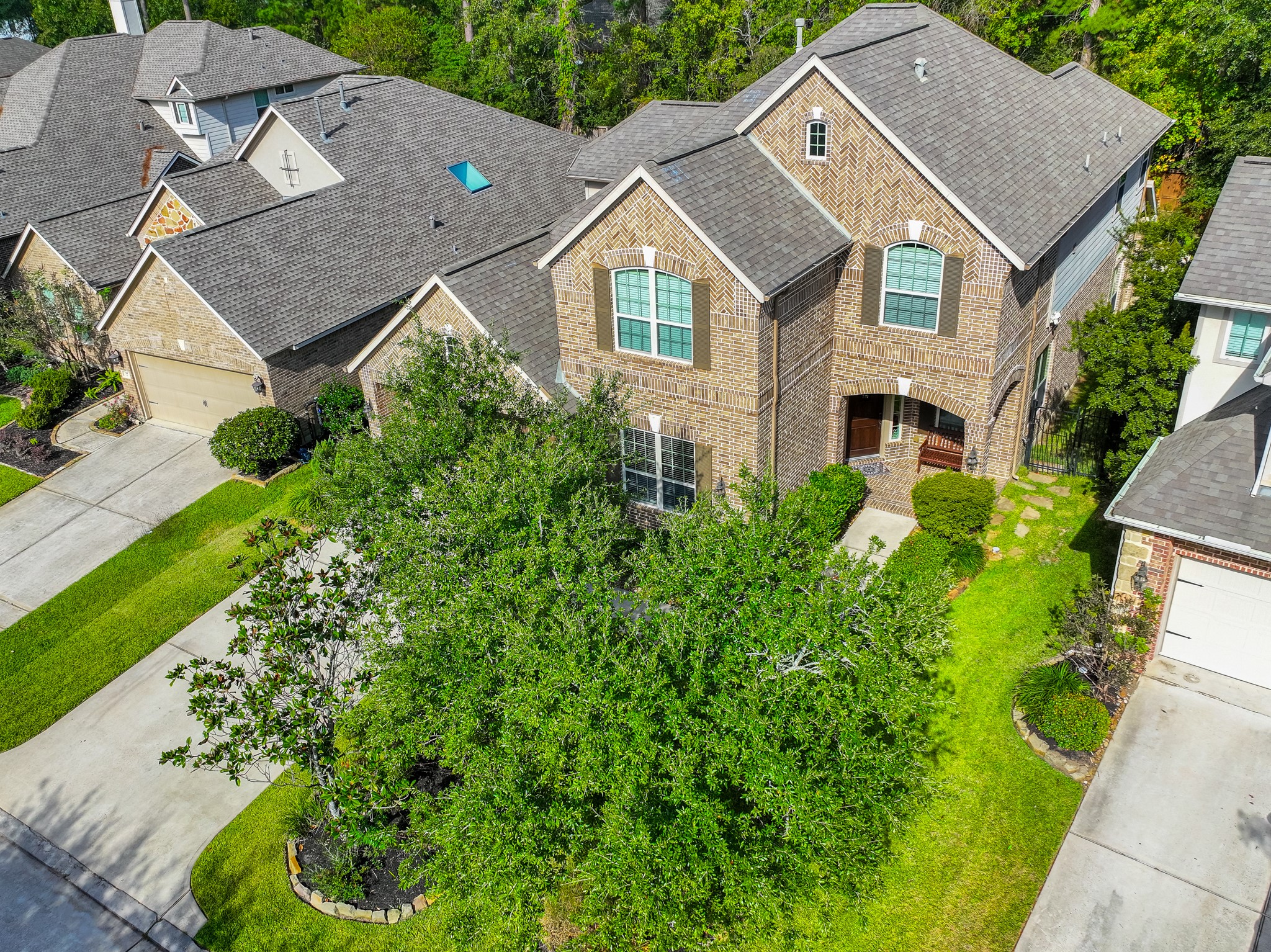 30 Fury Ranch Place The Woodlands, TX 77375 - Photo 3 of 47 This inviting two-story brick home features a well-maintained front yard with lush greenery and mature trees. It includes a spacious driveway leading to a two-car garage. The neighborhood appears peaceful and well-kept, ideal for family living.