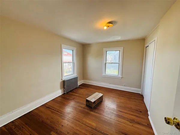 a view of an empty room with window and wooden floor