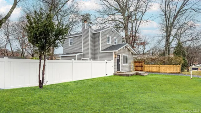 a view of a house with a big yard and large tree