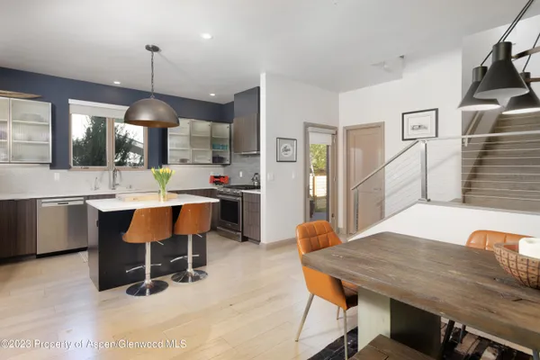 a dining hall with stainless steel appliances kitchen island granite countertop a table chairs and a refrigerator