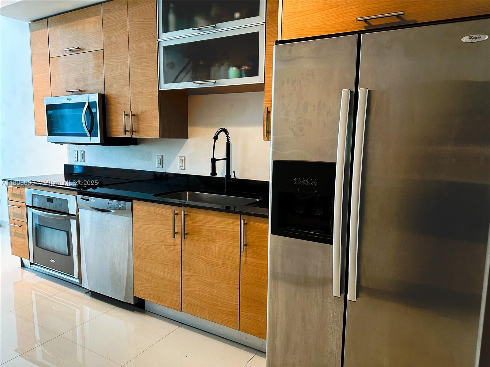 60 Southwest 13th Street, Unit 3418 Miami, FL 33130 - Photo 7 of 16 a kitchen with stainless steel appliances granite countertop a refrigerator a stove and a sink with wooden floor