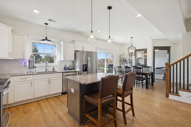 a large kitchen with granite countertop lots of counter space dining table and stainless steel appliances