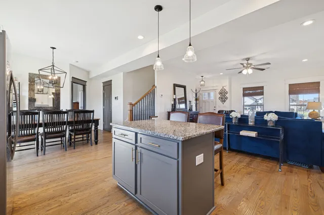 a kitchen with kitchen island granite countertop a table chairs sink and cabinets
