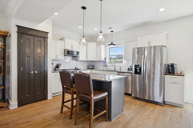 a kitchen with kitchen island granite countertop wooden floors and refrigerator