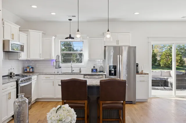 a kitchen with refrigerator a stove a sink and chairs