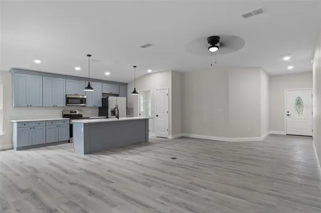 a large kitchen with a large counter top space a sink stainless steel appliances and cabinets