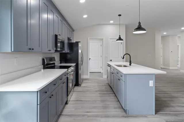 a large kitchen with kitchen island a wooden floor and a chandelier