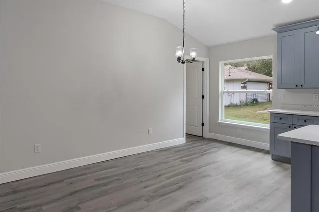 an empty room with wooden floor ceiling fan and windows