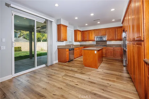 a kitchen with stainless steel appliances granite countertop a refrigerator a sink dishwasher a oven with wooden cabinets and wooden floor