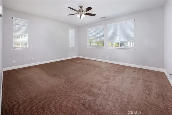 an empty room with windows and ceiling fan