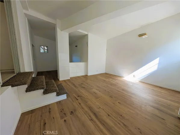 a view of a big room with wooden floor and windows