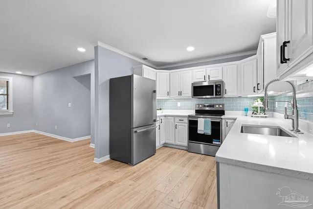 a kitchen with a refrigerator a stove top oven a sink and dishwasher with wooden floor