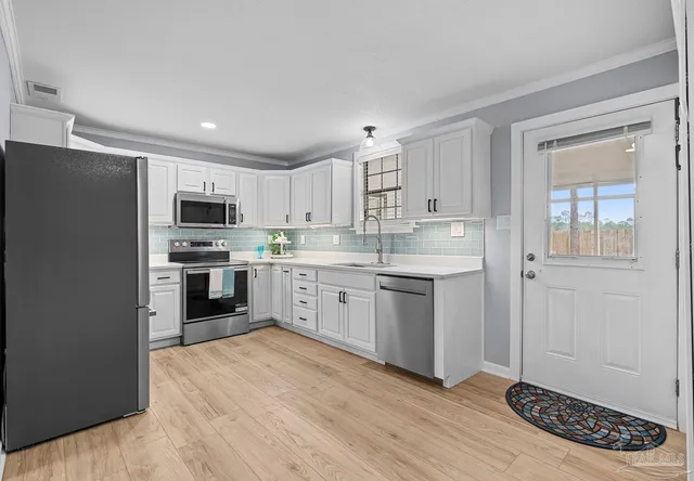 a kitchen with granite countertop a sink cabinets and stainless steel appliances