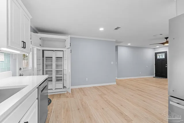 a view of empty room with wooden floor and fan