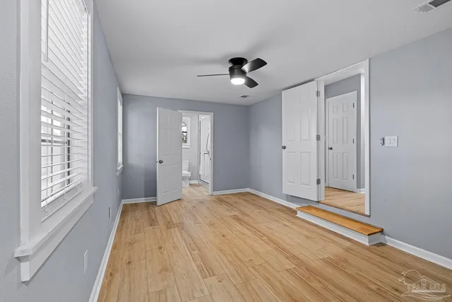 a view of empty room with wooden floor and fan